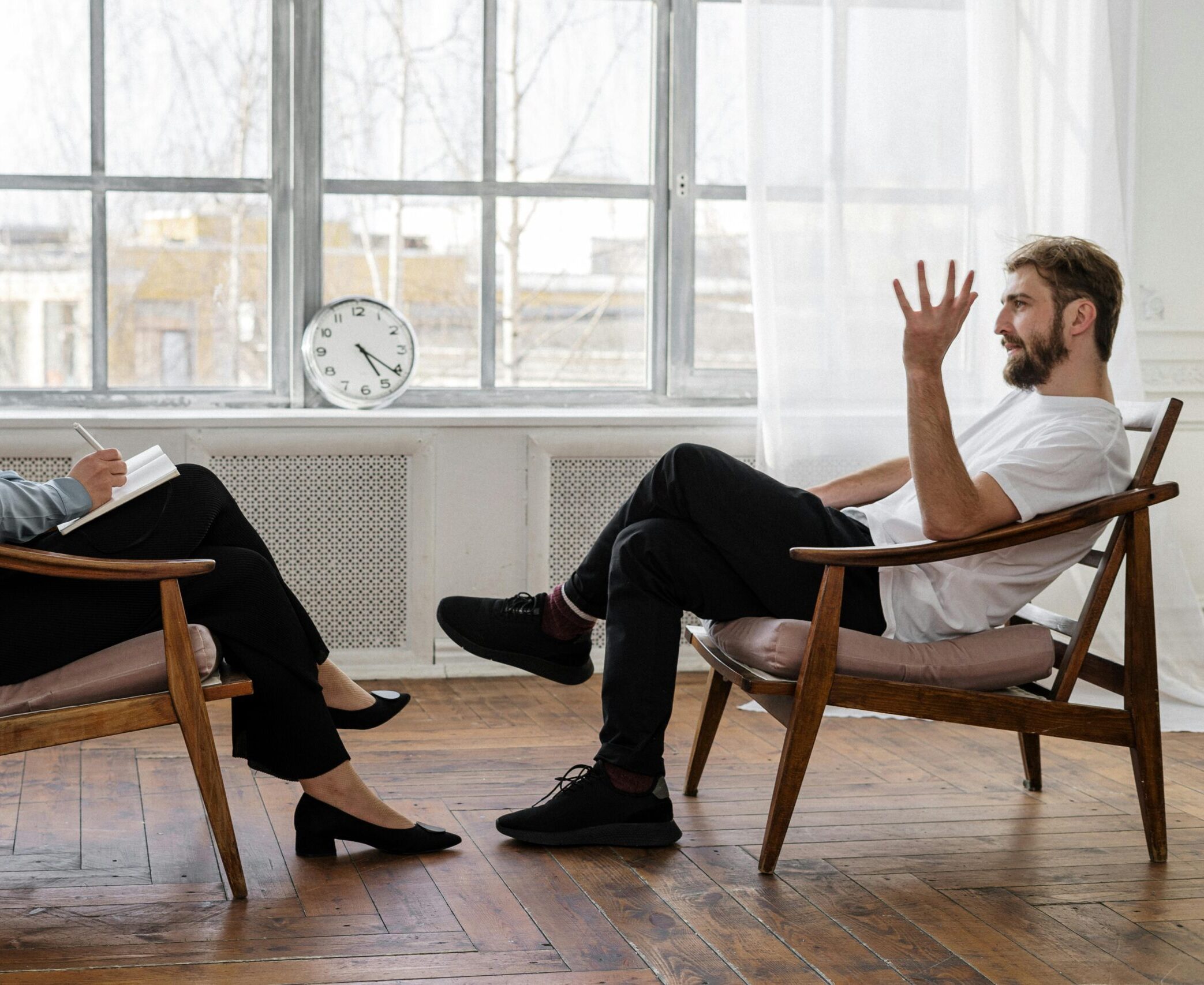 A therapist engaging in a counseling session with a male patient to support mental health.